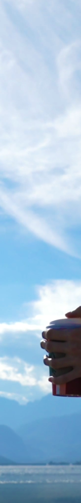 Female sitting by lake drinking coffee